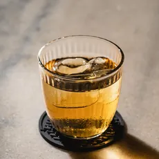 Copo baixo de Cachaça e Amaro com gelo, sobre mármore