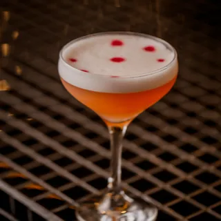 Taça do drink Enchanté com espuma e três pontos de bitters