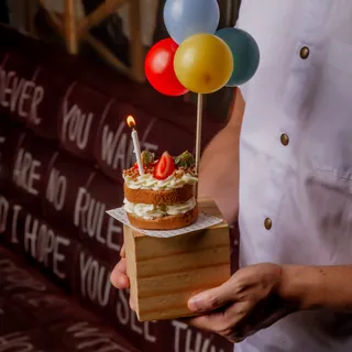 Mini naked cake com vela acesa e morango no topo